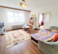 Living room in a family house with a TV, sofa, and wooden table on a carpet.