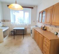 A kitchen in a family house with a wooden kitchen unit and a window without curtains.