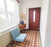 Entrance hall in a family house with a flower pot, a blue chair, and checkered tiles.