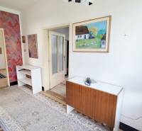 A hallway in a family house with antique furniture, colorful wallpaper, and a tapestry.