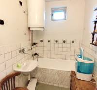 Bathroom in a family house with a bathtub, sink, washing machine, and water heater.