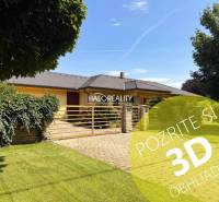 A family house in Komárno with a spacious garden, a paved driveway, and a hedge.