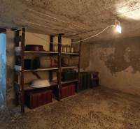 Basement with shelves in a cottage with stairs and basic equipment.