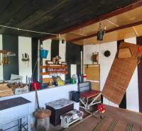 Interior of a cabin with a kitchen area, wall shelves, and a stove.
