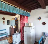 The interior of a cabin with a wooden ceiling, a blue curtain, and a white appliance.