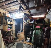 Storage space in a shed with tools and wooden shelves.