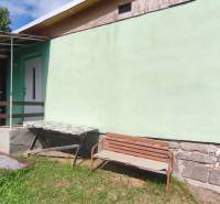 The cottage on Strhárska Street in Modrý Kameň with a wooden bench and a green fence.