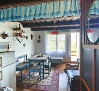 The interior of a cottage with a retro refrigerator, microwave, blue furniture, and a carpet in the living area.