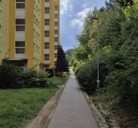 Yellow apartment building on Moskovská Street in Banská Bystrica next to the sidewalk and greenery.