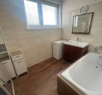 Bathroom in a 3-room apartment with a bathtub, mirror, and wood decor on the floor.