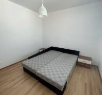 Bedroom in a 3-room apartment with a bed, nightstands, and a hanging light fixture.