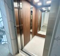 An open elevator in a 3-room apartment with wooden paneling and lighting.
