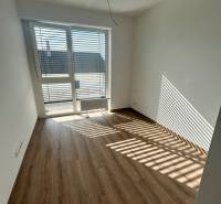 A room in a 3-room apartment with laminate flooring and a large window.