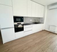 A kitchen in a 3-room apartment with white cabinets, appliances, and wooden flooring.