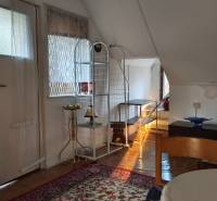 Interior of a cabin with a bed, table, wood, carpet, and decorative lamp.
