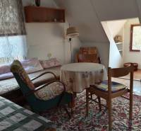 In a cozy cabin, there are chairs, simple armchairs, and a table on the carpet.