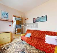 A room in a 4-room apartment with a sofa, carpet, and entrance to the kitchen.