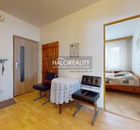 The hallway of a 4-room apartment with wooden furniture, a table, and an entrance to the bedroom.
