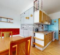 A kitchen in a 4-room apartment with wooden furniture and a dining table.