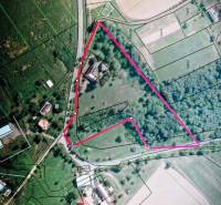 An aerial photograph shows a construction site bordered by a line, near family houses.