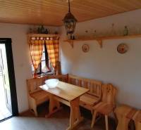 The rustic interior features a wooden bench and table, with furniture complementing the atmosphere of a family home.