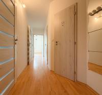 A hallway in a 3-room apartment with wooden flooring, white doors, and a mirror.