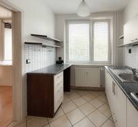 A kitchen in a 3-room apartment with light tiling and furniture.