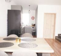 Dining room in a family house with a wooden table, kitchen, and stairs.