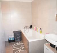 A bathroom in a family house with a bathtub, a sink, and storage baskets for laundry.