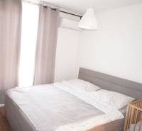 Bedroom in a family house with a large bed, air conditioning, and a baby crib.
