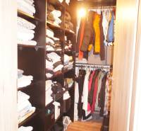 A wardrobe with shelves and hangers full of clothes in a family house.