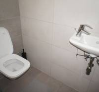 A toilet with a sink in a family house is tiled with minimalist furnishings.
