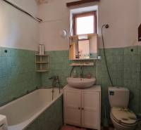 A bathroom in a family house with a bathtub, sink, and toilet, green tiles.