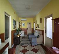 A hallway in a family house with yellow walls, a mirror, and furniture.