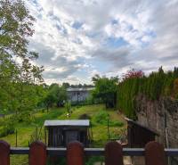 The garden of a family house on Partizánska Street in Malý Krtíš with greenery and a wooden fence.