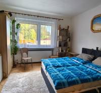 Bedroom in a family house with a bed, wardrobe, carpet, and decorations on the walls.