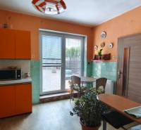 A kitchen in a family house with orange cabinets and a dining area.