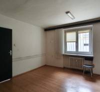 Office space with wooden flooring, white walls, and a window with a shade.
