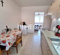 Kitchen in a 2-room apartment with a dining table, stove, and coffee maker.