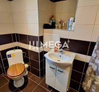 Bathroom with a shower curtain and a small sink in a 2-room apartment.