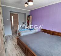 A bedroom in a two-room apartment with a wooden bed and a purple wall.