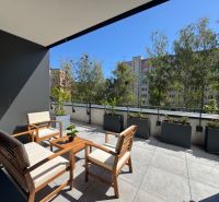 A terrace with wooden garden furniture surrounded by greenery on Popradská Street in Košice.