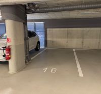Underground parking lot with a parking space near a car and a fire extinguisher.