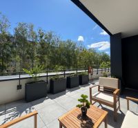 Terrace of a 1-room apartment with a view of Popradská Street in Košice, surrounded by greenery.