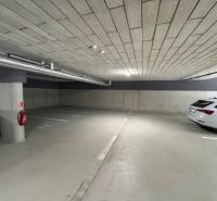 Underground garage with parking spaces, concrete walls and ceiling, two parked vehicles.