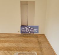 An empty room with wooden flooring in a 3-room apartment with open doors.