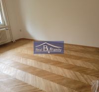 An empty room in a 3-room apartment with wooden parquet flooring and a radiator.