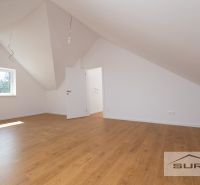 An attic room in a family house with a wooden decor floor and a slanted ceiling.