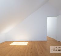 Attic room with white walls and a wooden decor floor in a family house.