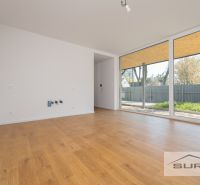 A room in a family house with large windows and a wooden decor floor.